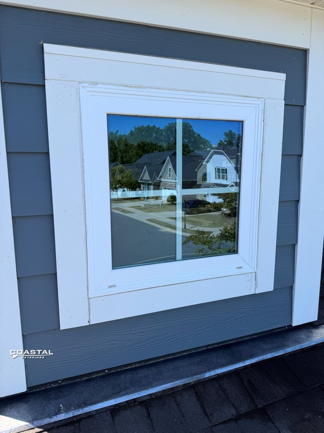 Window cleaned to a mirror-clear finish on a gray-sided home
